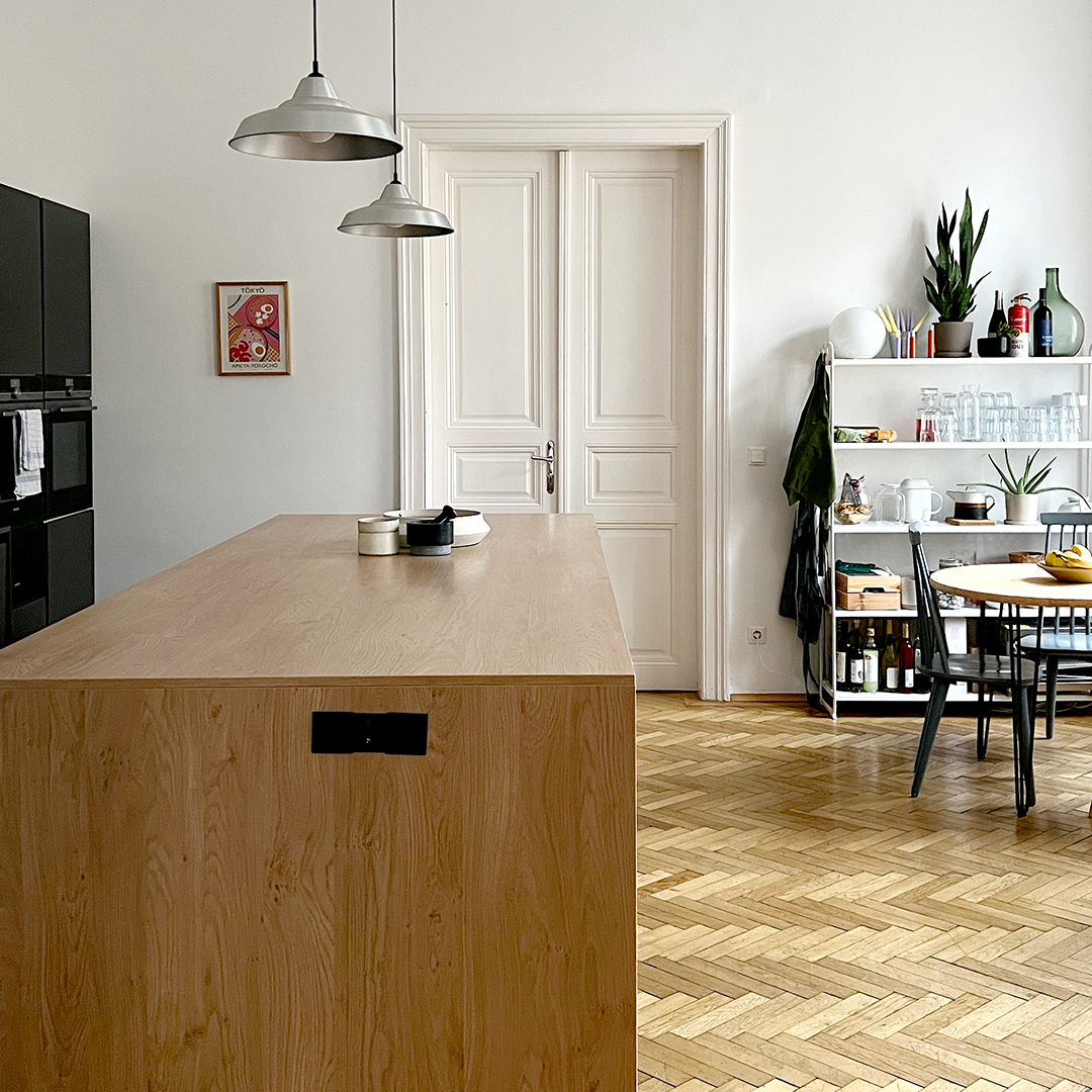 Großer Workshopraum im Altbau-Studio in Wien mit Holzboden, großer Arbeitsfläche und Atelierküche für kreative Events und DIY Workshops.