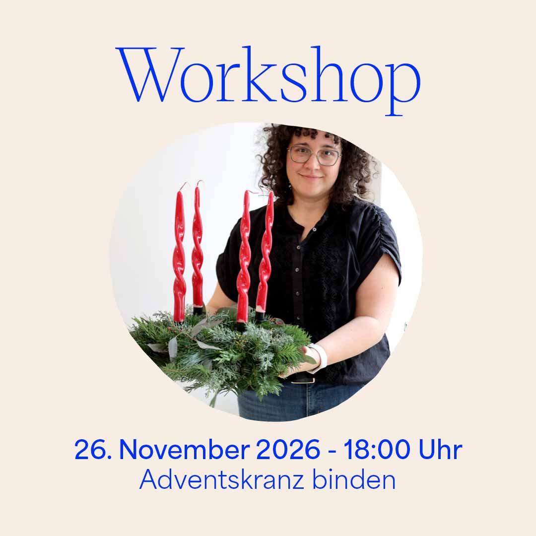 Grafik für den we love handmade Workshop 'Adventskranz binden' am 26. November 2026. Ein kreisrundes Foto zeigt eine stolze Kursteilnehmerin mit ihrem fertig gebundenen Adventskranz mit roten Gedrehten Kerzen. Darüber steht 'Workshop', darunter '26. November 2026 - 18:00 Uhr Adventskranz binden'.