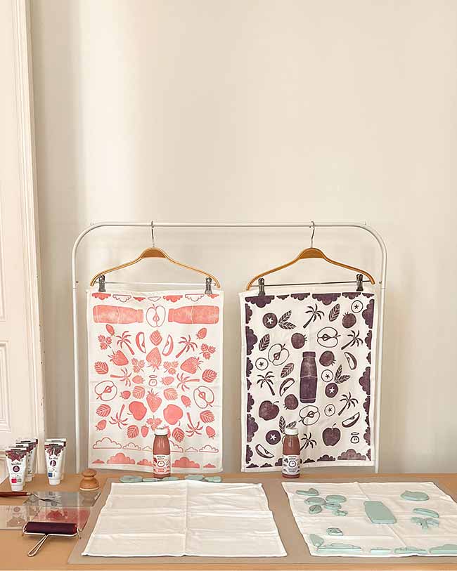 DIY-Station für Textildruck mit bedruckten Geschirrtüchern, Innocent-Smoothie-Flaschen, Linolfarben und Motivstempeln.